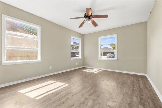 a view of empty room with wooden floor and fan