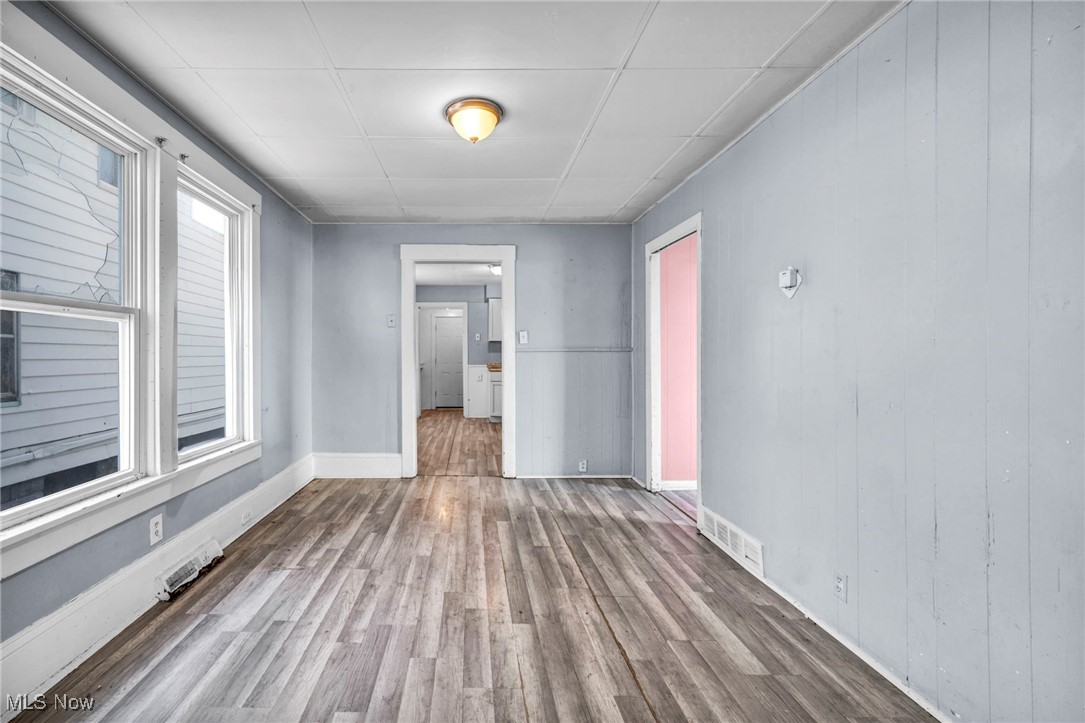 3405 Roehl Avenue Cleveland, OH 44109 - Photo 14 of 50 Empty room featuring wood finished floors, a paneled ceiling, and wooden walls