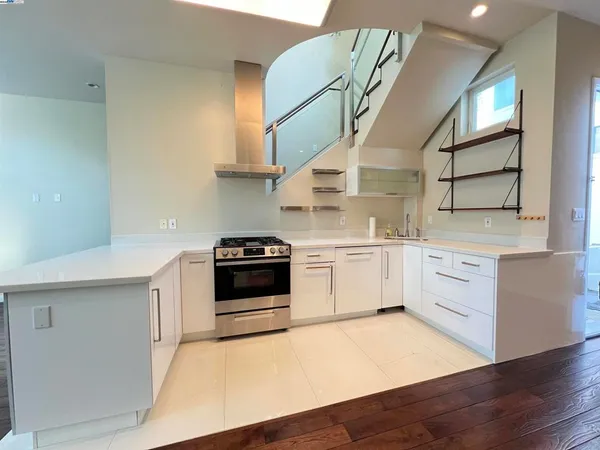 a kitchen with stainless steel appliances a white stove top oven cabinets and a wooden floor