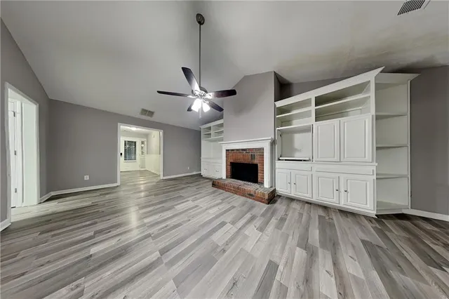 a view of empty room with wooden floor and fireplace