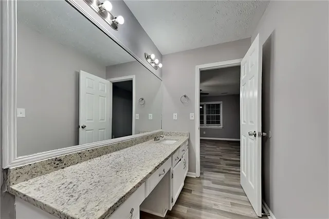 a bathroom with a granite countertop sink and white cabinets