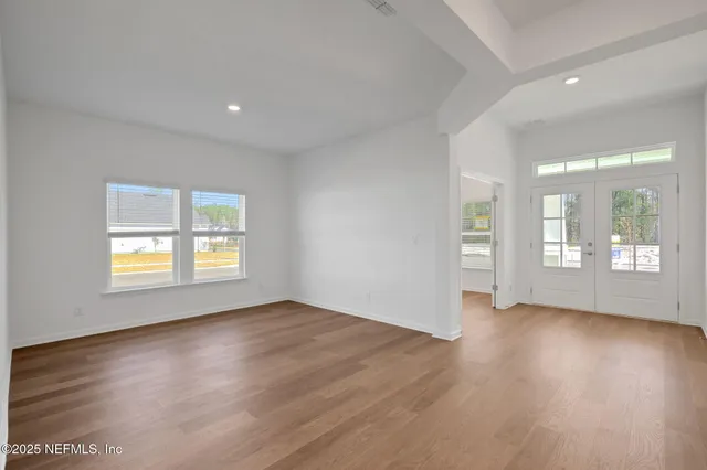 an empty room with wooden floor and windows