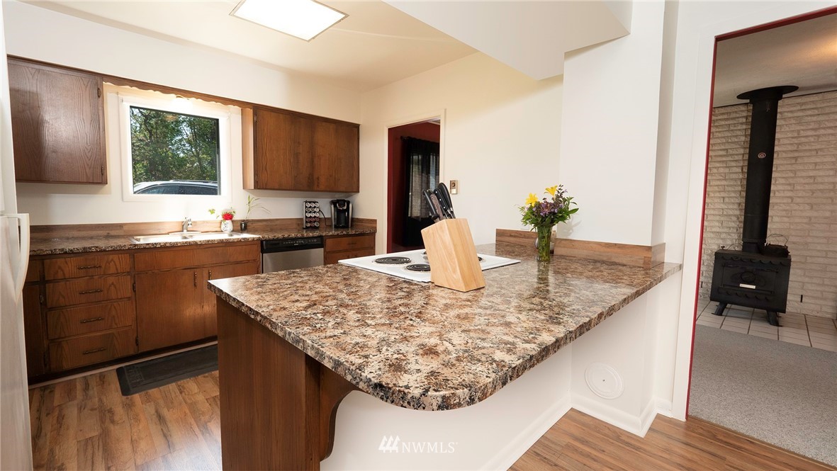 1849 Trigg Road Ferndale, WA 98248 - Photo 12 of 38 a kitchen with kitchen island granite countertop a sink and a wooden cabinets