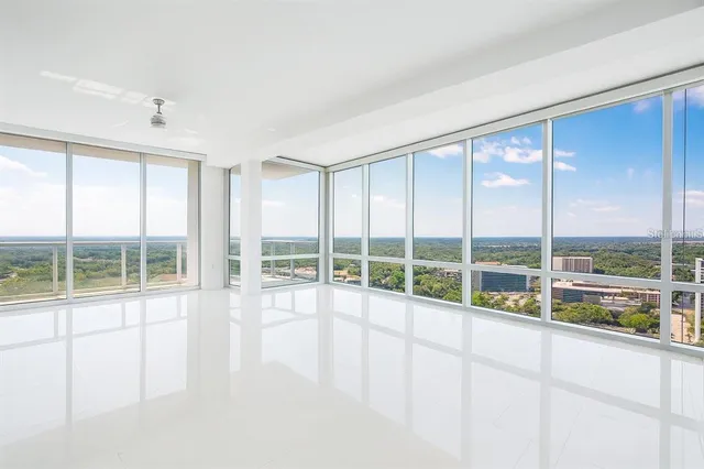 a view of an empty room with wooden floor and windows