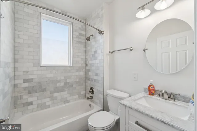 a bathroom with a granite countertop sink a toilet and shower