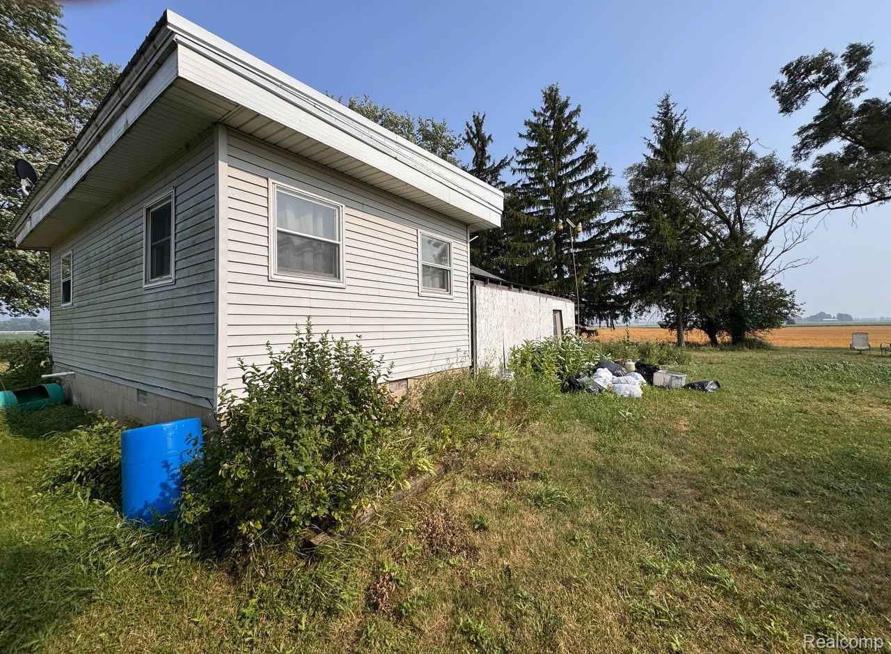 4703 North Byron Road Lennon, MI 48449 - Photo 23 of 25 Exterior featuring light-colored siding, multiple windows, a foundation, and a surrounding grassy area