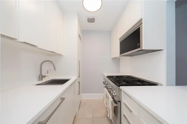 a kitchen with stainless steel appliances granite countertop a sink and a stove top oven with wooden floor