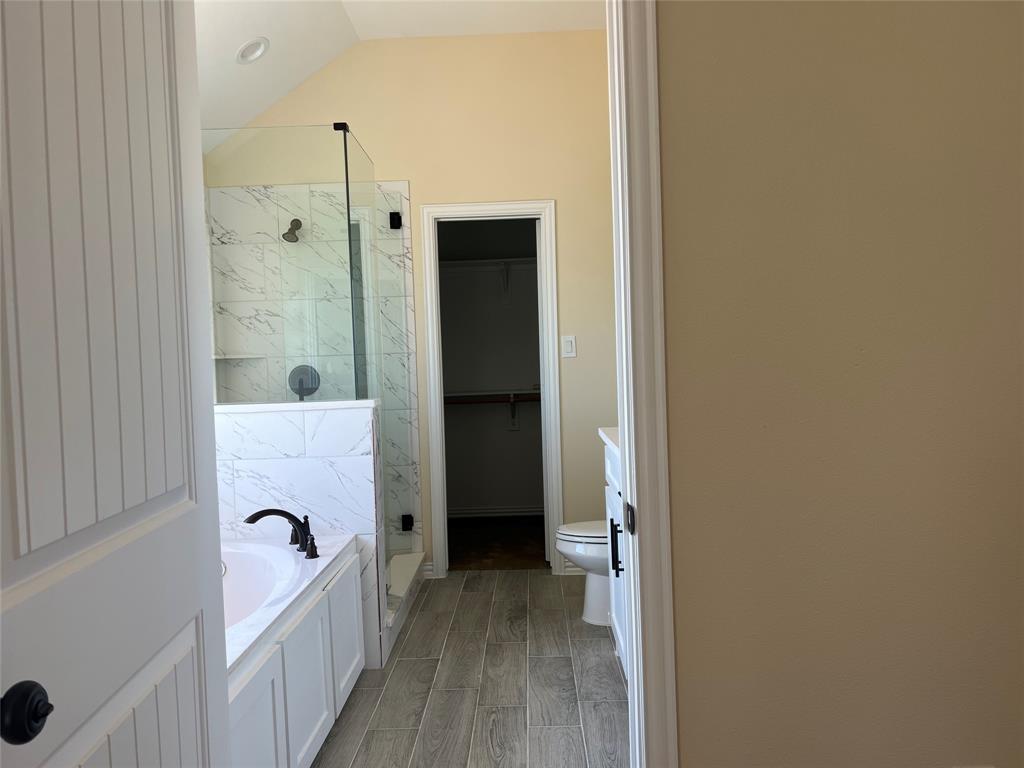 8008 County Road 1058 Rice, TX 75155 - Photo 13 of 25 Bathroom featuring a soaking tub with matte black fixtures, a walk-in shower with clear glass enclosure and marble-look tile surround, light wood-finish flooring, and a white vanity with integrated sink and black hardware