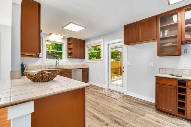 a view of an empty room with kitchen and a window