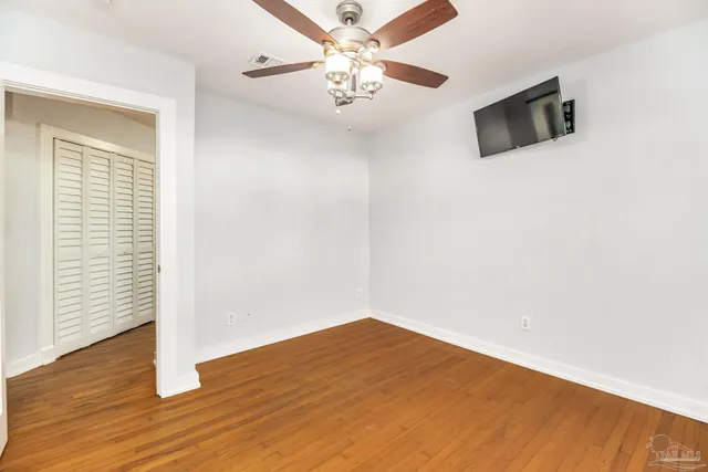a view of empty room with wooden floor and ceiling fan