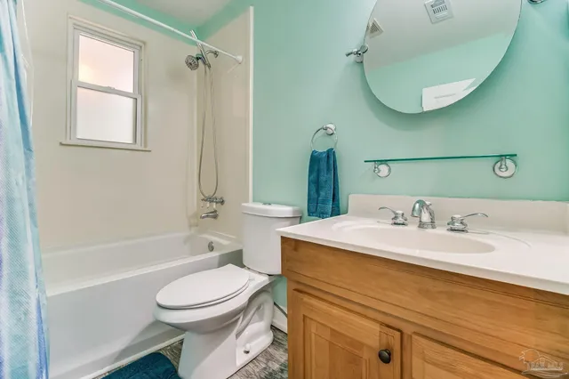 an empty room with wooden floor chandelier fan and windows