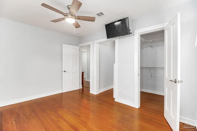 a view of empty room with wooden floor and fan