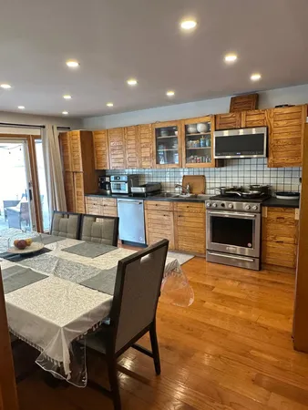 a kitchen with stainless steel appliances granite countertop a stove top oven a sink dishwasher a dining table and chairs with wooden floor