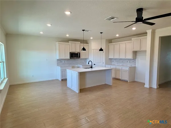 a large kitchen with stainless steel appliances kitchen island a large counter top and a stove with wooden floor