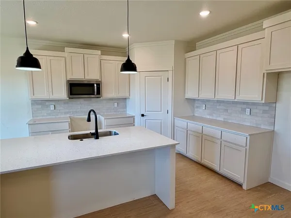 a kitchen with kitchen island granite countertop a sink a stove and cabinets