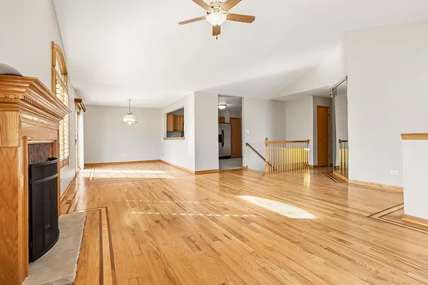 a view of an empty room with wooden floor and a fireplace