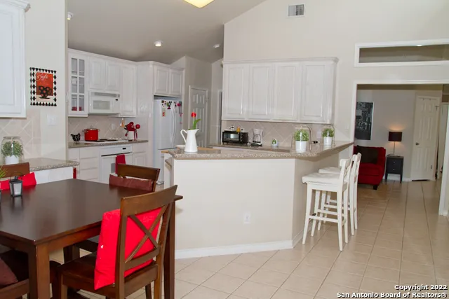 a kitchen with stainless steel appliances granite countertop a stove a sink dishwasher and a dining table with cabinets