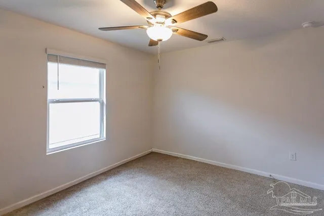 an empty room with a window and a fan