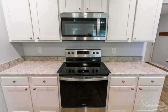 a kitchen with granite countertop white cabinets and appliances