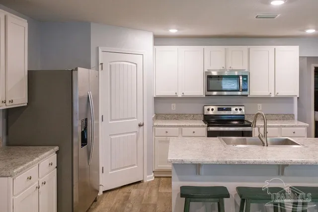 a kitchen with kitchen island granite countertop a refrigerator stove microwave and cabinets
