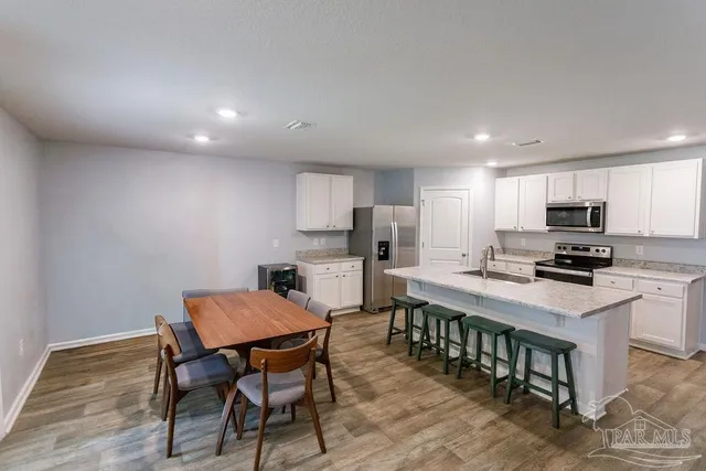 a kitchen with stainless steel appliances a dining table chairs and granite counter tops