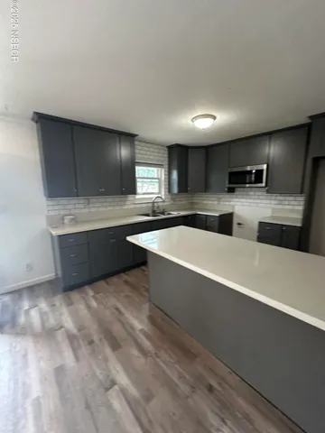 a large kitchen with kitchen island a sink stainless steel appliances and cabinets