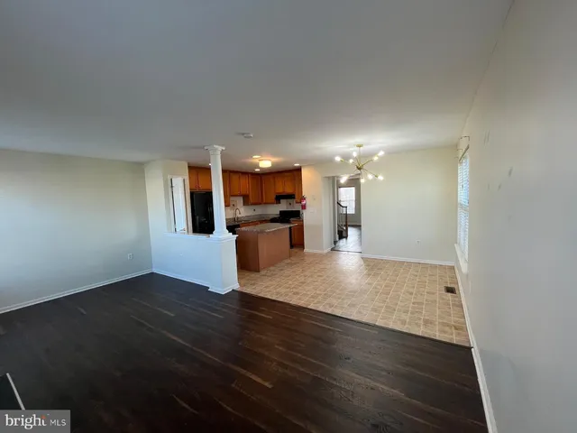 an empty room with wooden floor chandelier and windows