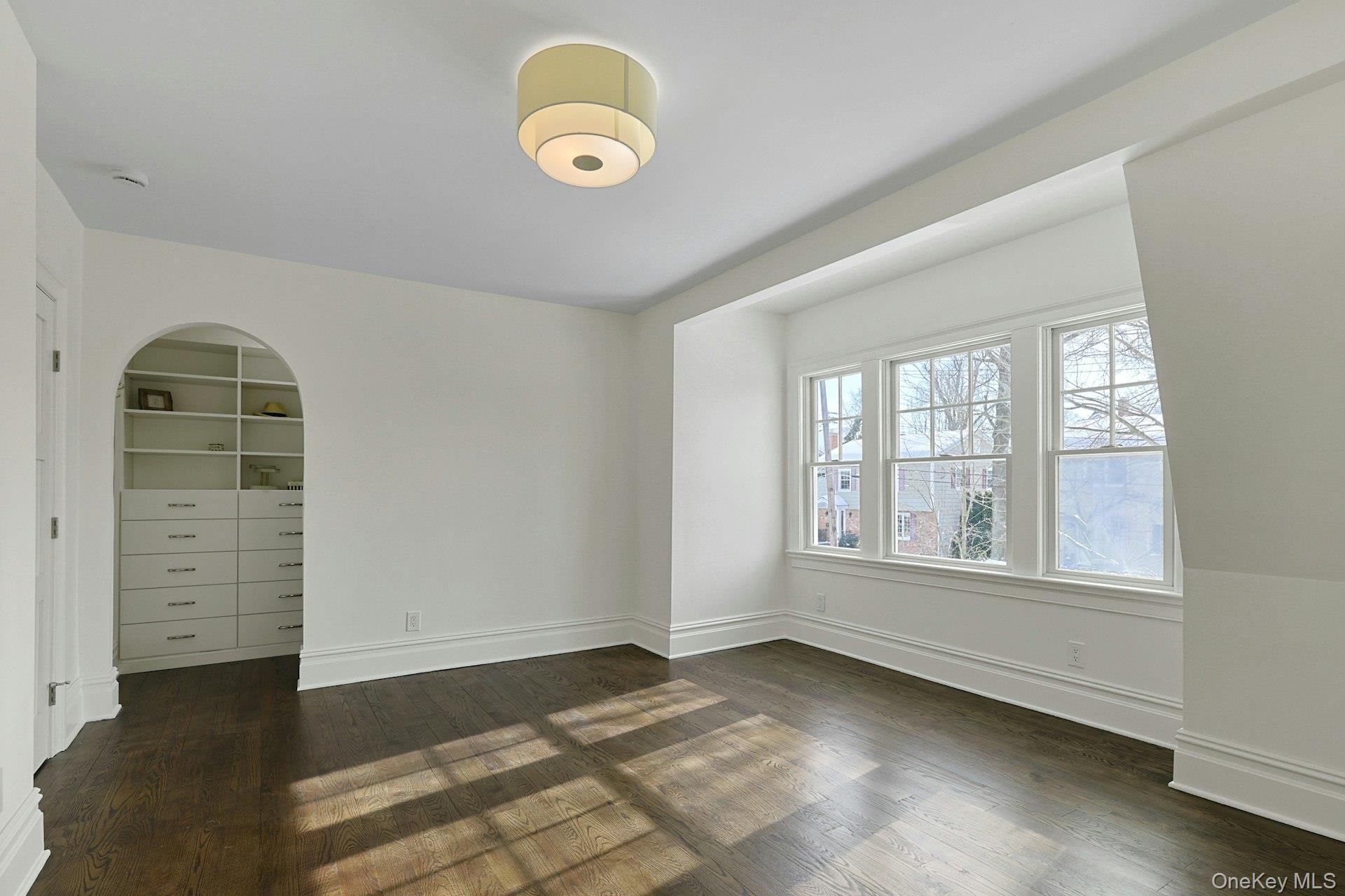 5 Henry Street Tuckahoe, NY 10707 - Photo 15 of 34 Light filled primary bedroom with a view of the walk in closet beyond the arched entryway.