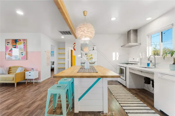 a kitchen with stainless steel appliances granite countertop a stove a sink dishwasher a dining table and chairs with wooden floor