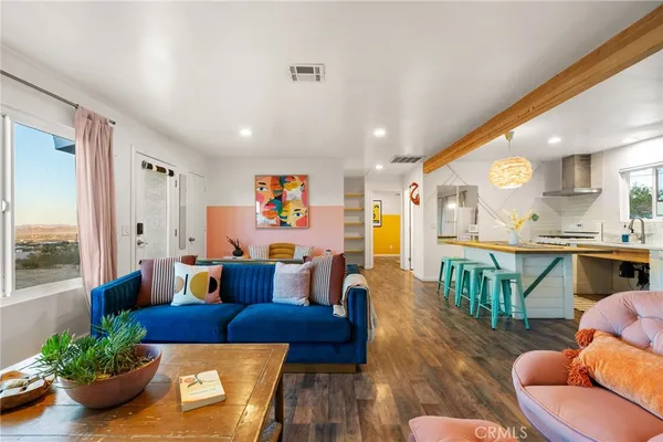 a living room with furniture kitchen view and a large window