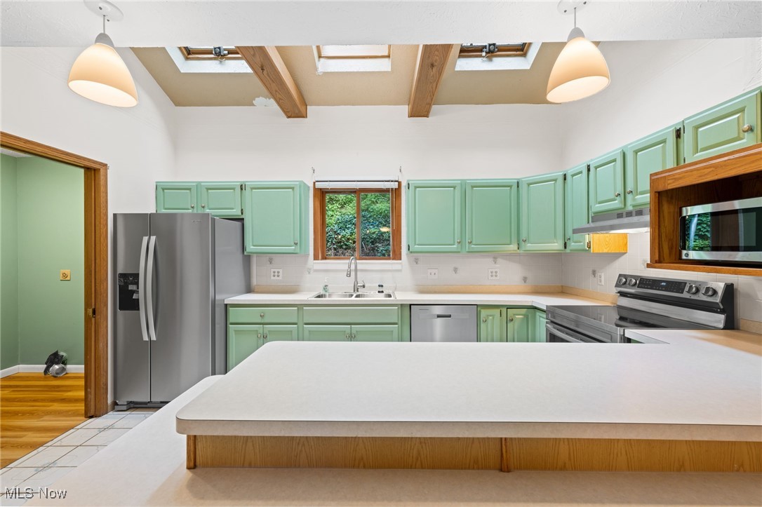 163 Burns Road Elyria, OH 44035 - Photo 6 of 37 Kitchen featuring stainless steel appliances, light countertops, beam ceiling, under cabinet range hood, and a peninsula