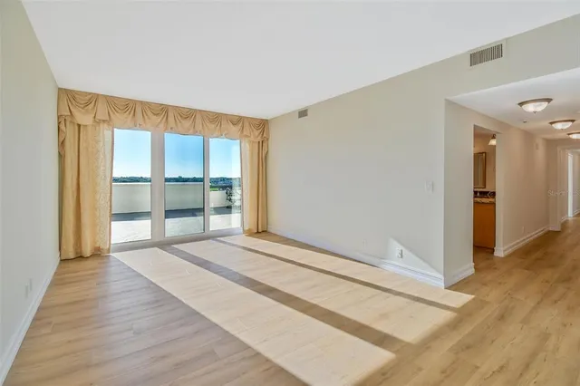 a view of an empty room with wooden floor and a window