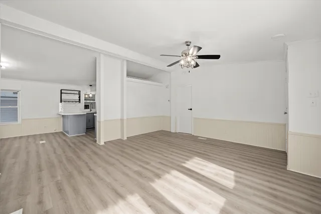 a view of empty room with wooden floor and ceiling fan