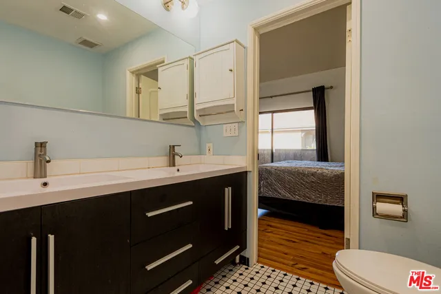 a en suite bathroom with a double vanity sink a mirror and a toilet