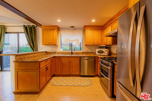 a kitchen with stainless steel appliances granite countertop a stove a sink and a refrigerator