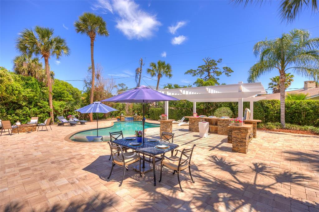 105 Riverside Drive Ormond Beach, FL 32176 - Photo 90 of 100 a view of a patio with a table and chairs under an umbrella with palm trees