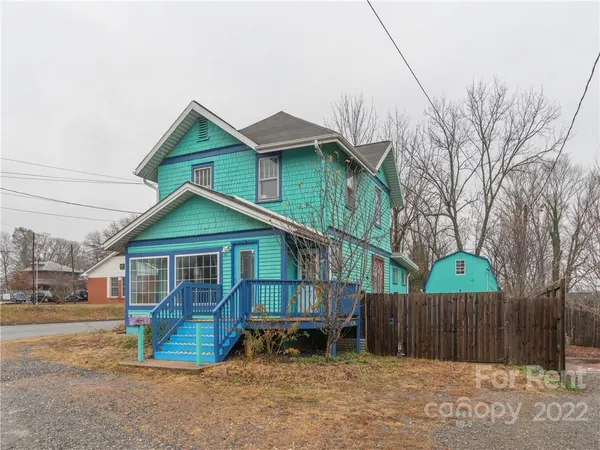 a view of a house with wooden fence next to a road