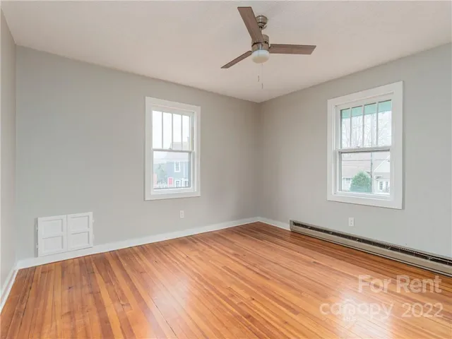 a view of empty room with wooden floor and fan