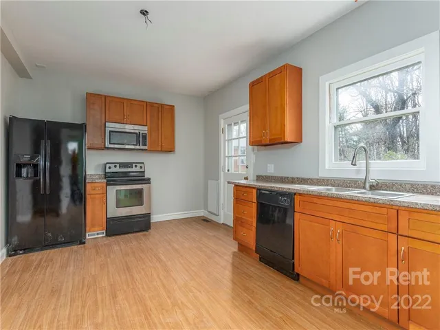 a kitchen with stainless steel appliances granite countertop a stove a sink and a refrigerator