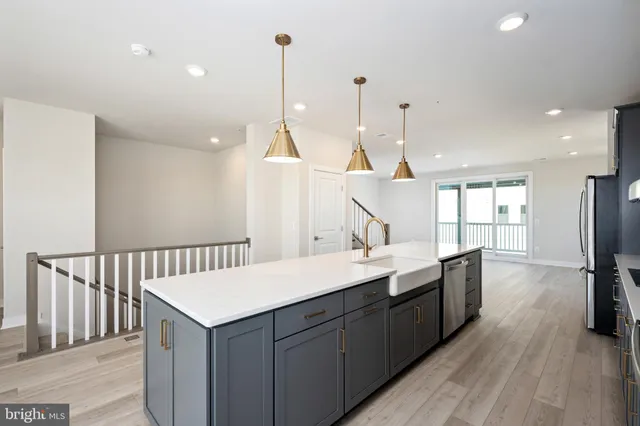 a kitchen with a sink a center island a wooden floor and a large window