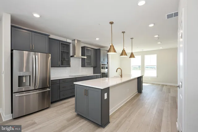 a large kitchen with a center island wooden floor stainless steel appliances and windows