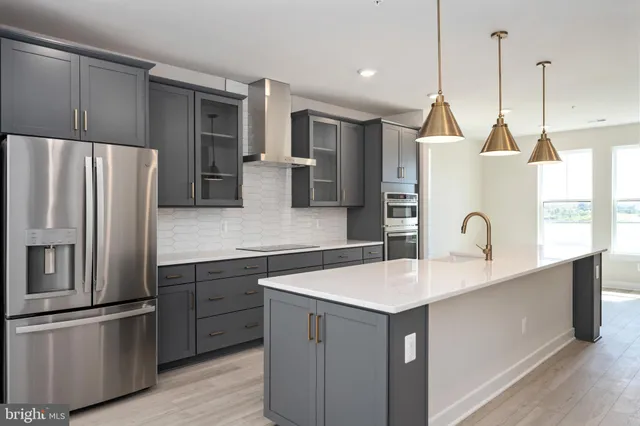 a kitchen with stainless steel appliances granite countertop a refrigerator a sink and a stove