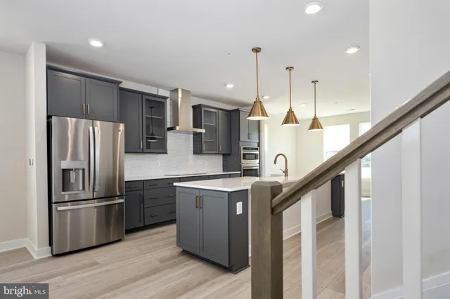a kitchen with stainless steel appliances kitchen island a refrigerator sink and wooden floor