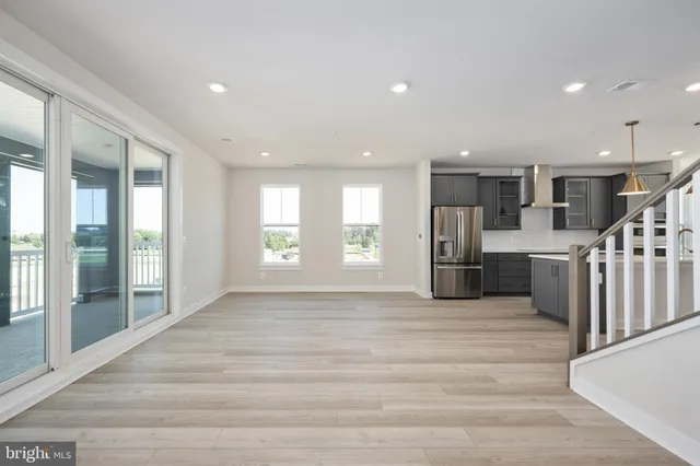 a view of an empty room with wooden floor and windows