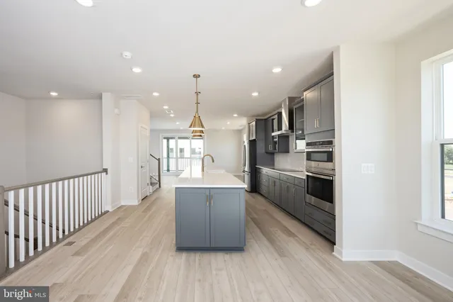 a kitchen with stainless steel appliances kitchen island wooden floors wooden cabinets and entryway