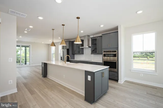 a large kitchen with stainless steel appliances kitchen island granite countertop a stove a sink a refrigerator and a dining table with wooden floor