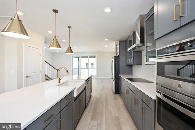 a large kitchen with stainless steel appliances kitchen island a large stove a sink dishwasher and a refrigerator with wooden floor