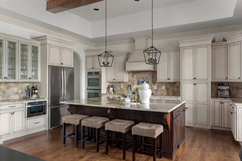 a kitchen with stainless steel appliances granite countertop a sink a stove a refrigerator and island with wooden floor