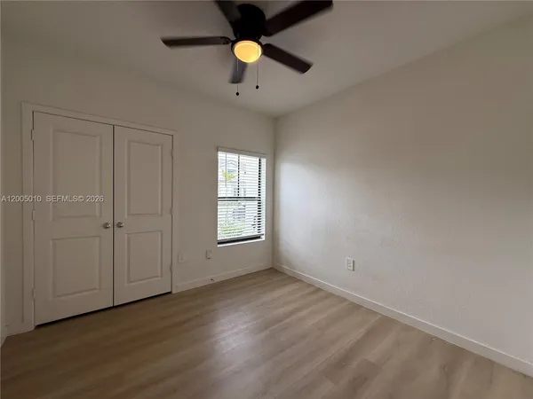 an empty room with wooden floor fan and windows