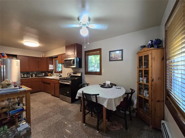 a kitchen with a dining table chairs and refrigerator